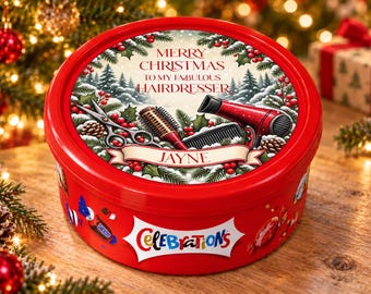 May include: A round red Celebrations chocolate tin featuring a festive lid with illustrations of scissors, a hairbrush, and a hairdryer. The text reads Merry Christmas to my fabulous hairdresser and the name Jayne on a banner.