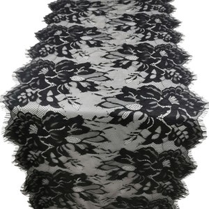 Pode incluir: Caminho de mesa de renda preta com um padrão floral. O caminho de mesa apresenta um design delicado e vazado com bordas onduladas. O intrincado padrão floral é visível em todo o comprimento, criando um acento elegante e decorativo.