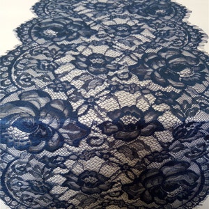 Könnte beinhalten: Marineblauer Tischläufer aus Spitze mit floralem Muster. Der Läufer besteht aus zarter Spitze und weist aufwendige Details auf. Die Kanten sind gewellt, was einen Hauch von Eleganz verleiht. Ideal für eine elegante Tischdekoration.