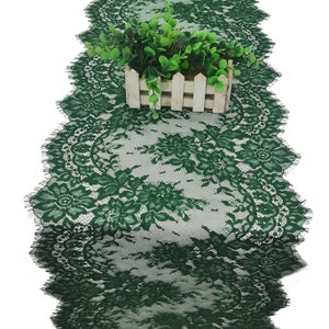 May include: A green lace table runner with a scalloped edge. The runner is made of delicate lace with a floral pattern.