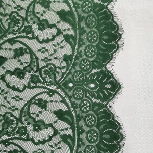 May include: Green lace trim with a floral pattern. The lace has a scalloped edge.