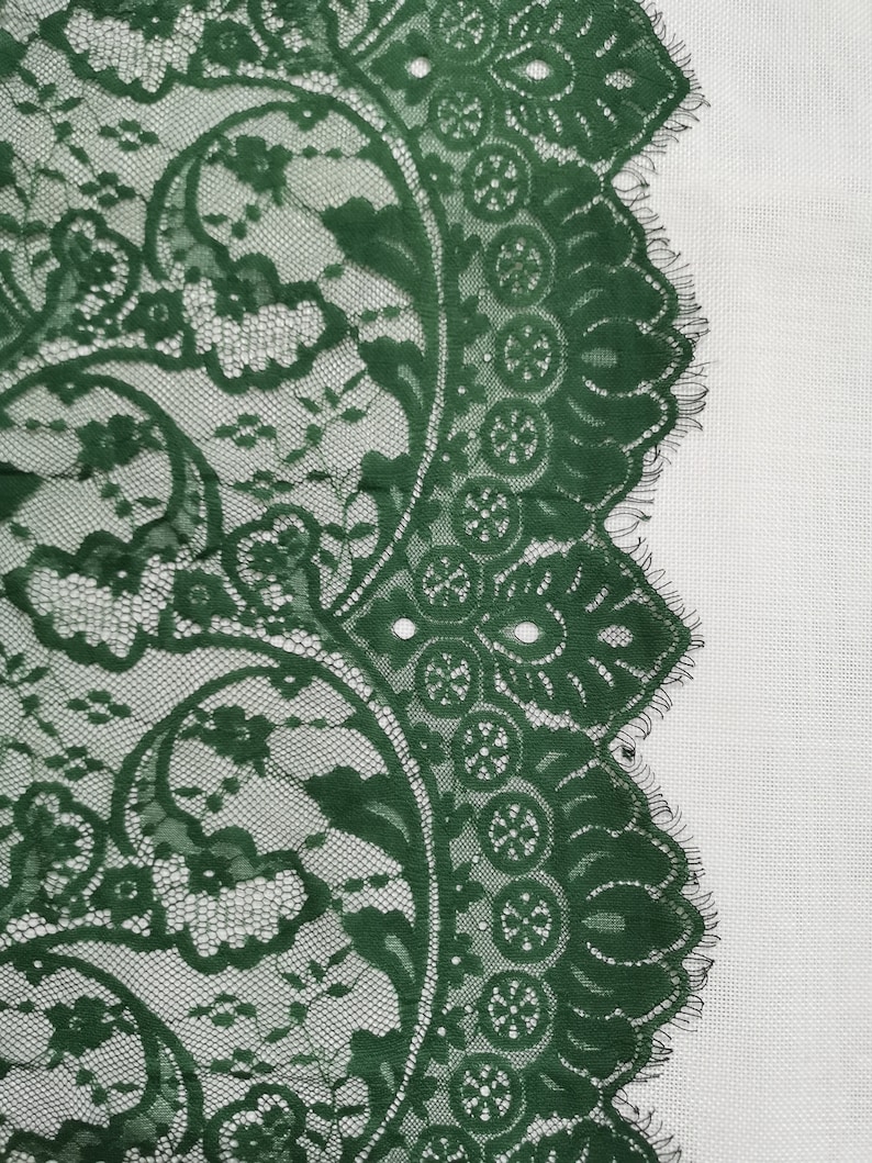 May include: Green lace trim with a floral pattern. The lace has a scalloped edge.