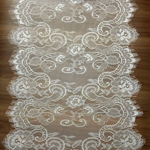 May include: White lace trim with a delicate floral pattern. The lace has a scalloped edge and is perfect for adding a touch of elegance to any project.