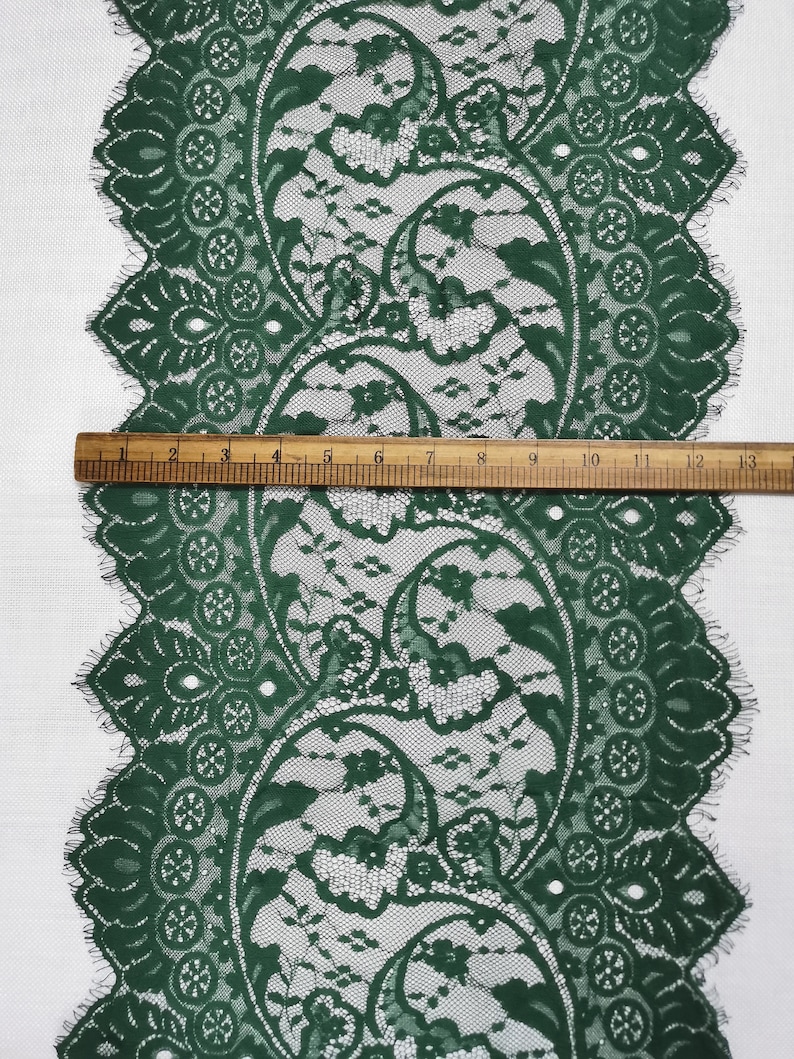 May include: Green lace trim with a paisley pattern. The lace is approximately 3.8 cm wide.