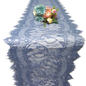Könnte beinhalten: Ein staubiger blauer Tischläufer aus Spitze mit einem gewellten Rand. Der Läufer ist mit einem Blumenmuster verziert und hat ein zartes, filigranes Design.