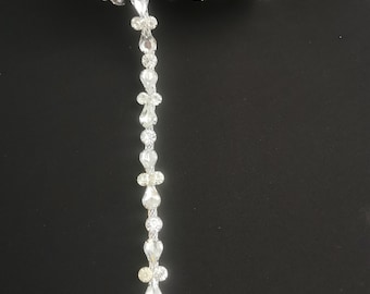 May include: A spool of clear rhinestone trim with a silver metal chain. The trim is made of small, teardrop-shaped rhinestones.