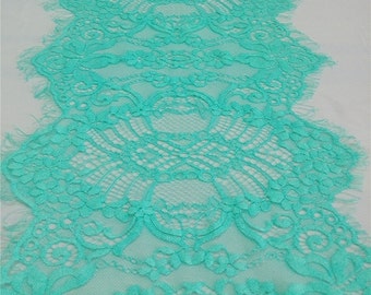 May include: Teal lace trim with a delicate floral pattern. The lace has a scalloped edge and is perfect for adding a touch of elegance to any project.