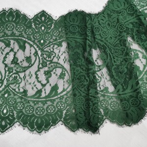 May include: Green lace trim with a delicate floral pattern. The lace has a scalloped edge and a frayed finish.