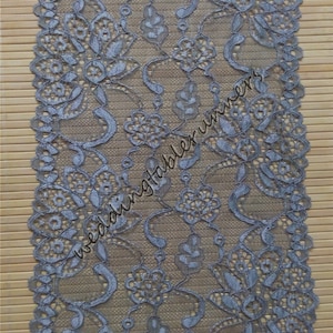 Könnte beinhalten: Nahaufnahme einer silbernen Spitzenborte mit Blumenmuster. Die Spitze ist zart und filigran, mit einem dezenten Schimmer. Sie ist perfekt, um jedem Projekt einen Hauch von Eleganz zu verleihen.