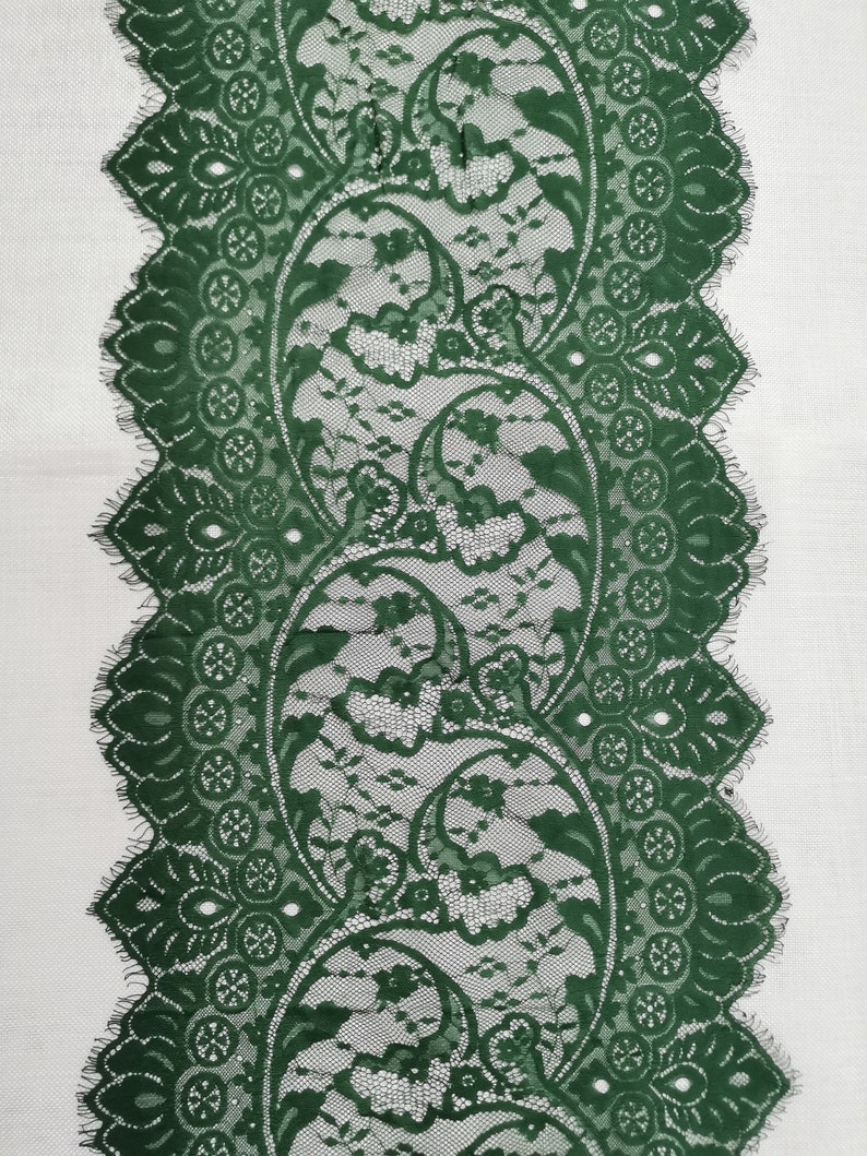May include: Green lace trim with a paisley pattern. The lace has a scalloped edge.