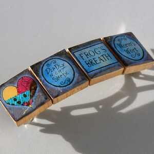 May include: A set of four wooden drawer pulls with blue and black painted designs. The pulls feature a heart, the words "Deadly Nightshade", "Frog's Breath", and "Worm's Wort".