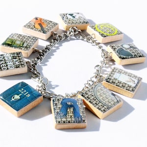 May include: A silver charm bracelet with nine square charms featuring images from the Sherlock Holmes series. The charms include a violin, a clock, a magnifying glass, a bottle of perfume, a scarf, a silhouette of Sherlock Holmes, a silhouette of a woman, the text "I am Sherlock", and the number "221B".