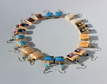 May include: A collection of 18 square wooden earrings with various colourful images printed on them. The earrings are arranged in a circle on a white surface.
