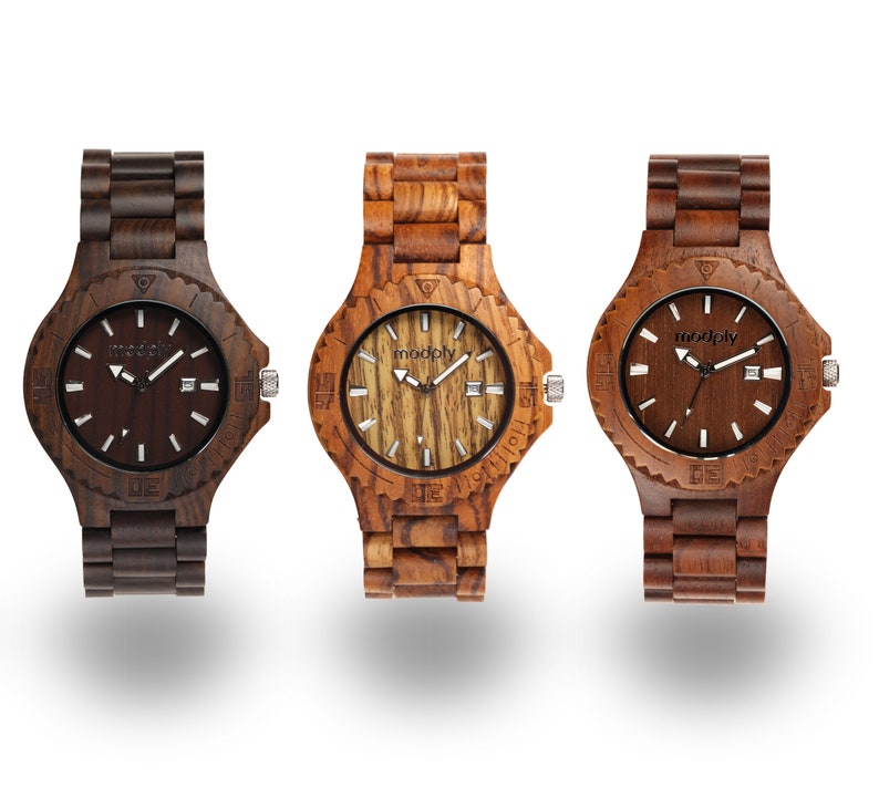 May include: Three wooden wristwatches with brown, light brown, and dark brown wood bands. The watch faces are all different, with one having a dark brown face, one having a light brown face, and one having a wood grain face. All watches have the word "modply" printed on the face.