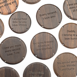 Puede incluir: Una colección de 10 fondos de reloj redondos de madera con varios mensajes grabados, incluyendo "Te amo más cada segundo", "Eres mi mayor aventura" y "Papá, te pertenezco".