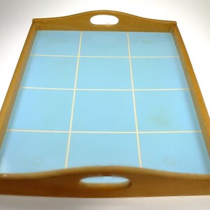 Puede incluir: Una bandeja de servir de madera con una superficie de azulejos de color azul claro. La bandeja tiene dos asas a los lados y una en la parte delantera.