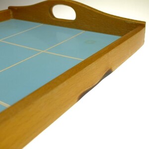 Puede incluir: Una bandeja de servir de madera con una superficie de azulejos de color azul claro. La bandeja tiene un asa en la parte superior y est&aacute; hecha de madera natural.