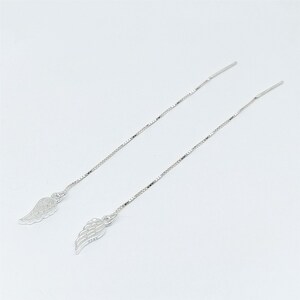 May include: A pair of silver threader earrings. Each earring has a small, detailed wing charm at the base of a delicate chain. The earrings are shown against a plain white background, highlighting their elegant design.