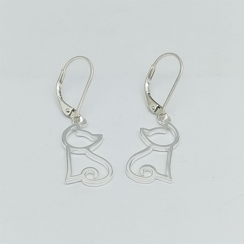 May include: A pair of silver cat silhouette earrings with leverback closures.