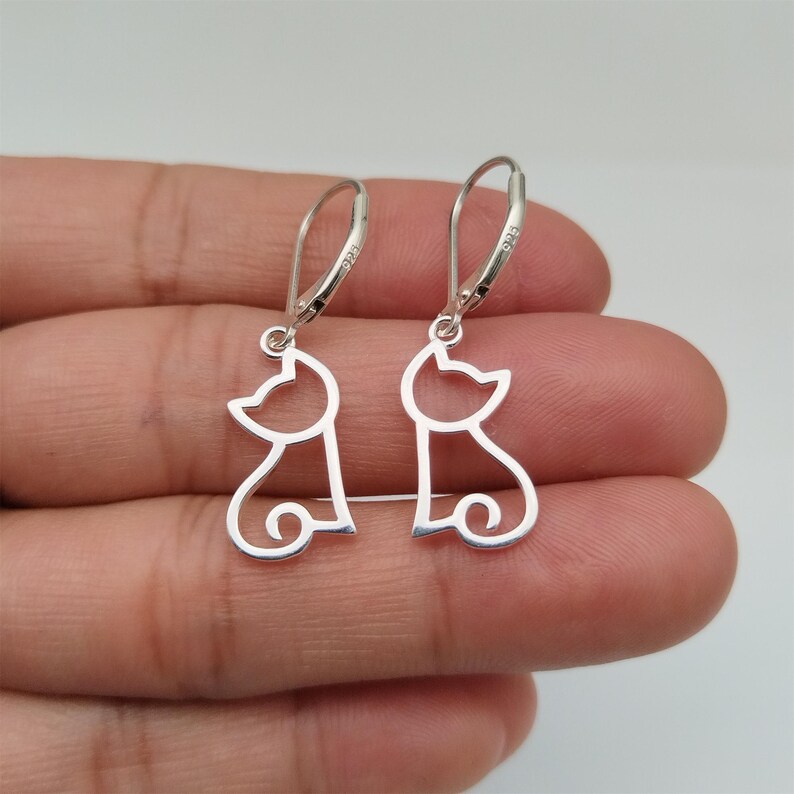May include: A pair of silver cat silhouette earrings. The earrings are dangle style with a simple cat outline.