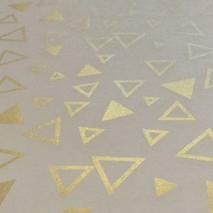 May include: A white background with a repeating pattern of gold triangles.