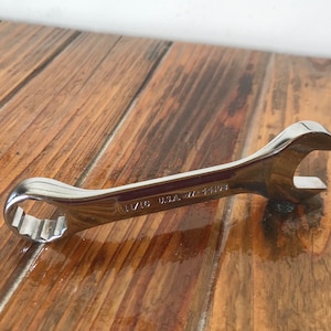 May include: A silver wrench with a 11/16 inch size marking. The wrench is on a wooden surface.