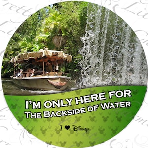 May include: Circular design featuring a boat on a river with a waterfall and lush greenery. Text reads "I'M ONLY HERE FOR THE BACKSIDE OF WATER" with "I ❤️ Disney" below. The background is green with Mickey Mouse icons.