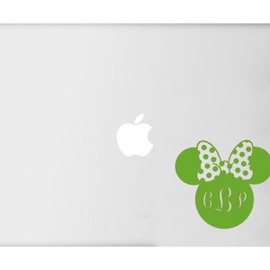 May include: A green decal in the shape of a mouse head with a polka dot bow and initials. The decal is on a laptop. The bow is white with green polka dots. The initials are in a script font.
