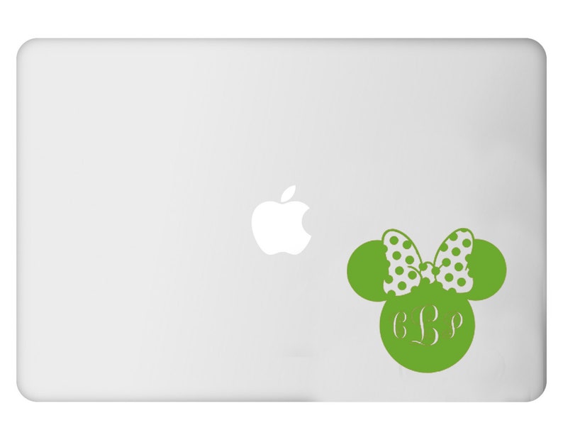 May include: A green decal in the shape of a mouse head with a polka dot bow and initials. The decal is on a laptop. The bow is white with green polka dots. The initials are in a script font.