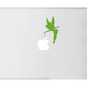 May include: A white laptop with a green silhouette of Tinkerbell holding a stem attached to a white apple logo. The fairy is depicted in a classic pose, with her wings spread and her dress visible.