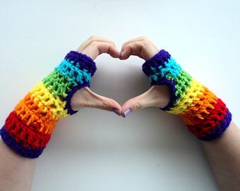 May include: A pair of rainbow crochet fingerless gloves with a heart shape formed by the hands wearing them.