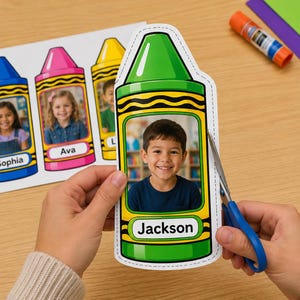 Op de afbeelding: Een groene, krijtvormige papieren uitknipsel met een foto van een lachend kind en de naam Jackson op een wit label. Het uitknipsel heeft een gestippelde rand om te knippen en wordt bijgeknipt met een schaar met blauwe handvatten.