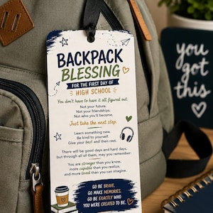 May include: A rectangular white tag with rounded corners, featuring dark blue and green text titled BACKPACK BLESSING FOR THE FIRST DAY OF HIGH SCHOOL. It includes illustrations of a coffee cup, books, and headphones, with inspirational text and the Bible verse Jeremiah 29:11.