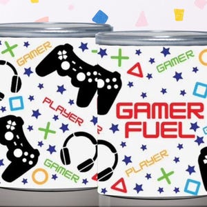 May include: Two cylindrical containers with silver lids. The containers are white with a pattern of blue stars, black game controllers, headphones, and the words "GAMER" and "PLAYER". The words "GAMER FUEL" are in red.