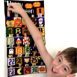 Könnte beinhalten: Ein schwarzer und gelber Halloween-Adventskalender mit Süßigkeiten in jeder Tasche. Der Kalender ist von 1 bis 30 nummeriert und zeigt Kürbisse, Geister und Fledermäuse. Ein Kind greift nach einem Bonbon.