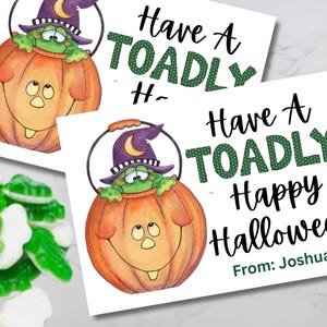 Könnte beinhalten: Zwei Halloween-Karten mit einer Cartoon-Fröschin in einem Kürbis mit Hexenhut. Auf den Karten steht "Have A TOADLY Happy Halloween" und "From: Joshua". Grüne und weiße Gummibonbons befinden sich in der unteren linken Ecke.