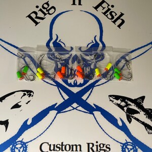 May include: A set of six fishing rigs with green, orange, and yellow beads. The rigs are packaged in clear plastic bags and are labeled "Rig 'n Fish Custom Rigs".