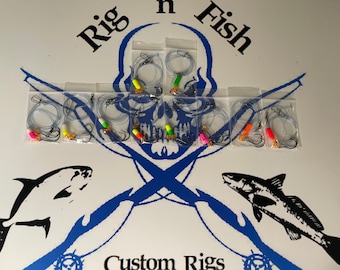 May include: A set of eight fishing rigs in clear plastic bags. Each rig has a clear line, two hooks, and a colorful bead. The rigs are arranged in two rows of four. The bags are labeled "Rig 'n Fish Custom Rigs".