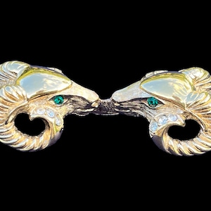 May include: A pair of gold-tone ram's head brooches with green and clear rhinestones.