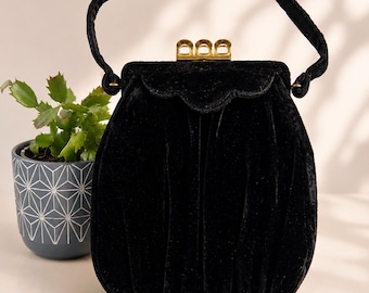 Bolso vintage de terciopelo negro de los años 30: cierre festoneado Art Déco y correa de muñeca.