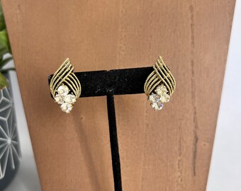 May include: Gold-toned vintage earrings with a woven design and clear crystal accents. The earrings have a teardrop shape with a cluster of crystals at the base. The earrings are displayed on a black earring stand.