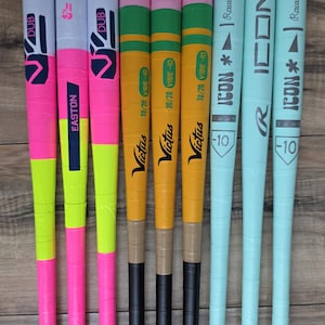 May include: A collection of eight baseball bats arranged side-by-side. Three bats feature pink and neon yellow patterns with Easton and DUB branding. Three yellow and green Victus Vibe bats are marked 30/20. Two light blue Rawlings Icon bats.