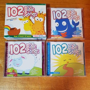 May include: Four children's music CDs titled "102 Bible Songs." The CD covers feature cartoon illustrations of a giraffe, a whale, a sheep, and a sun. The CD cases are clear plastic, and the boxes are colorful.