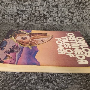 May include: A vintage paperback book titled "Tales of Power" by Carlos Castaneda. The cover features a colorful illustration of a butterfly with a purple, pink, and blue background.