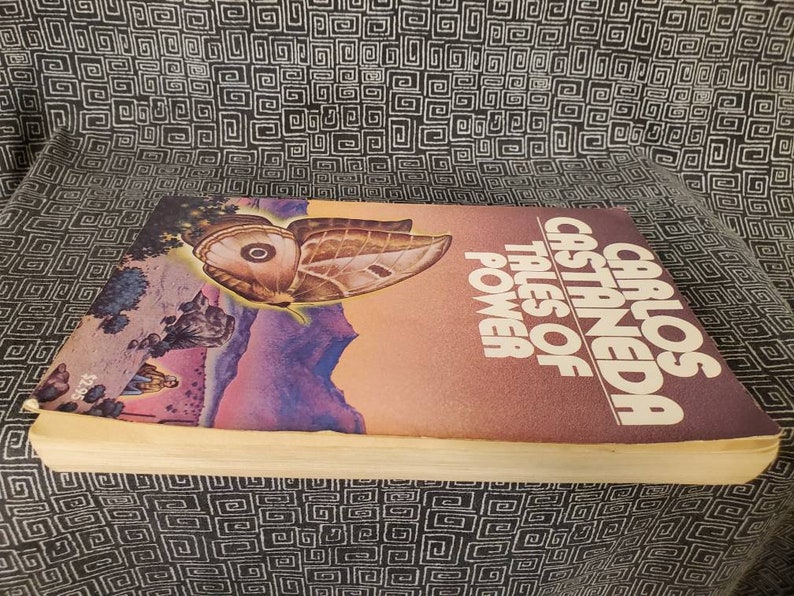 May include: A vintage paperback book titled "Tales of Power" by Carlos Castaneda. The cover features a colorful illustration of a butterfly with a purple, pink, and blue background.