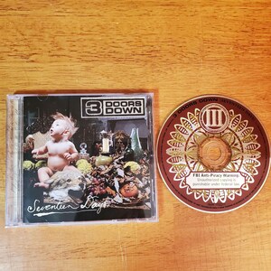 May include: A CD case and disc from the band 3 Doors Down. The CD case features the album title "Seventeen Days" with an image of a baby and various objects. The CD itself is brown with the band's logo and text.
