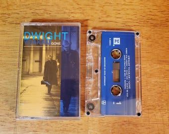 May include: A Dwight Yoakam Gone cassette tape with its clear plastic case. The insert features a photograph of a person in a hat and coat walking. The cassette itself is blue with white text listing tracks including Sorry You Asked.