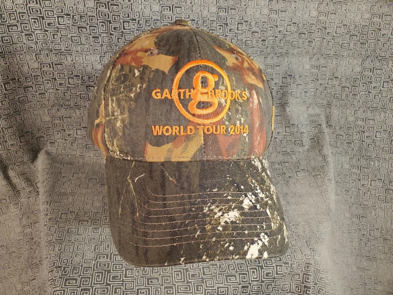 Peut inclure: Une casquette de baseball camouflage avec un logo brod&eacute; orange qui dit "Garth Brooks World Tour 2014".