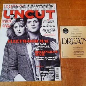 May include: A magazine cover featuring Fleetwood Mac with the text "The Saga Continues. Meet... Buckingham Movie" and a CD with the text "Free CD!"  The magazine cover is a black and white photo of Fleetwood Mac members Lindsey Buckingham and Stevie Nicks.  The magazine is titled "Uncut" and has a gold sticker with the text "15 months of the month".  A gold sticker with the text "Dreams" is also visible.