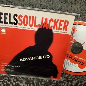 May include: A red CD case with the title "EELS SOULJACKER" and the text "YOU LITTLE PUNKS THINK YOU OWN THIS TOWN". The case includes a CD with the title "SOULJACKER" and the text "ADVANCE CD".
